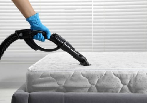 Woman disinfecting mattress with vacuum cleaner indoors, closeup. Space for text